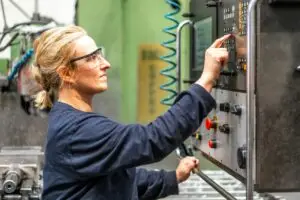 Female factory worker operator working in numerical control sector, touching control panel
